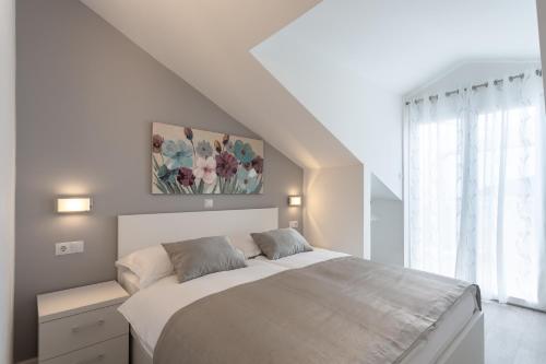 a white bedroom with a large bed and a window at Villa Stonehouse 2 in Milna