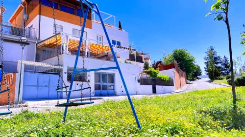 a swing in the grass in front of a building at CASA LOS ABETOS cerca de la Alhambra y Sierra Nevada in Cenes de la Vega