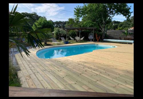 una piscina con pavimento in legno e terrazza in legno di La villa cassy a Lanton