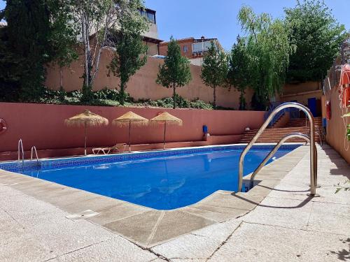 塞內斯德拉維加的住宿－CASA LOS ABETOS cerca de la Alhambra y Sierra Nevada，一座带遮阳伞的游泳池位于一座建筑旁边