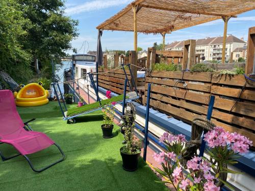 un patio avec une chaise rose et une aire de jeux dans l'établissement Péniche à 25 mn de Paris, à Creil