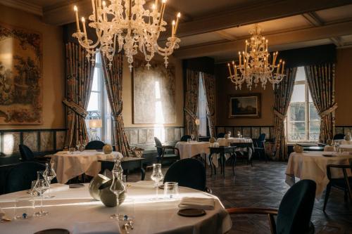a dining room with tables and chandeliers at Château Neercanne - Oostwegel Collection, member of Relais and Châteaux in Maastricht