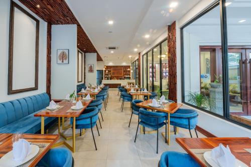 um restaurante com mesas de madeira e cadeiras azuis em Homewood Hotel By Seuya Hotel em Siem Reap