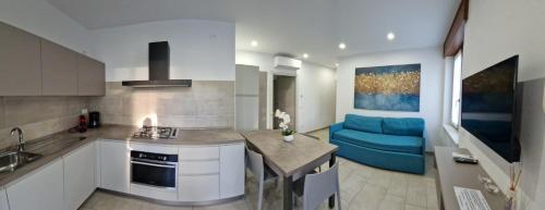 Cabà Holiday Bardolino Gritti في باردولينو: مطبخ وغرفة معيشة مع أريكة زرقاء