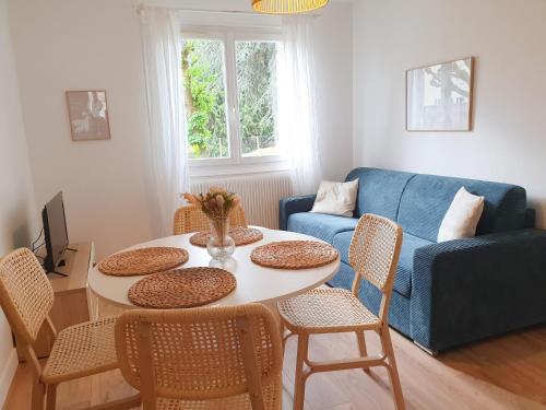 ein Wohnzimmer mit einem Tisch, Stühlen und einem blauen Sofa in der Unterkunft Beautiful 2 Bedroom apartment in a quiet residence in Garches