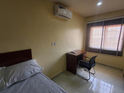 a bedroom with a bed and a desk and a chair at Lagos 247 Apartment in Lekki
