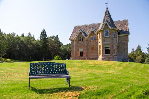 a bench sitting in front of a large house at Inveroykel Lodge at Rosehall in Rosehall