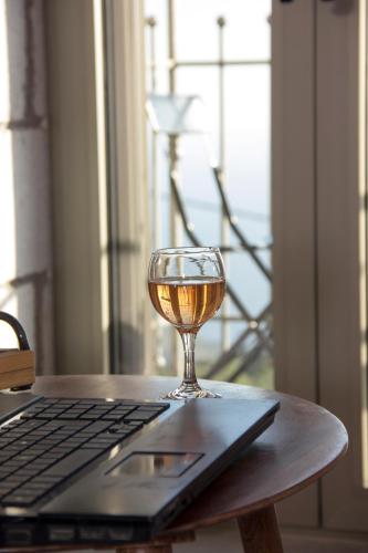 a glass of wine sitting on a table next to a laptop at Lithorama Residence Mani Complex in Koúmani