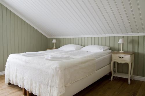 a bed with white sheets and pillows in a room at Lónsleira Apartments in Seyðisfjörður