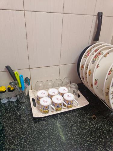 a tray of cups on a counter next to a wall at COIMBATORE 2BHK AC Private Villa By Shivalaya -Kovaipudur- in Coimbatore