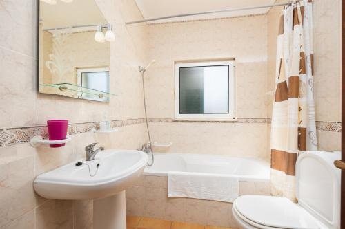 a bathroom with a sink and a tub and a toilet at Villa Sol Nascente in Porches