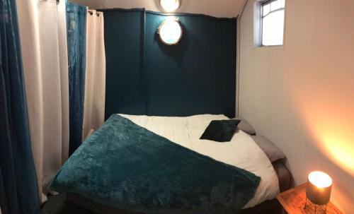 ein kleines Schlafzimmer mit einem Bett mit grünem Kopfteil in der Unterkunft Péniche à 25 mn de Paris in Creil
