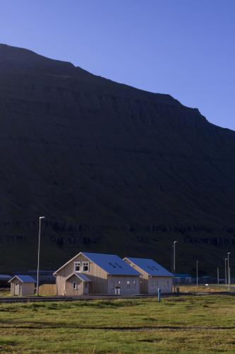a house in a field with a mountain in the background at Lónsleira Apartments in Seyðisfjörður