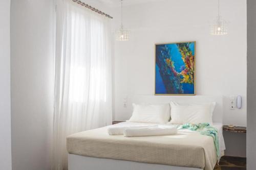a white bedroom with a bed with white curtains at Scorpios Hotel & Suites in Samos