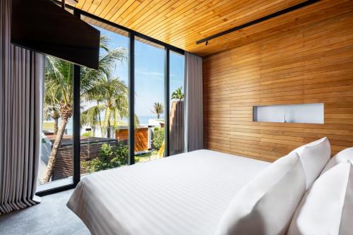 a bedroom with a large bed and large windows at Casa De La Flora - SHA Extra Plus in Khao Lak