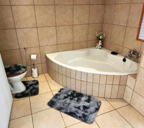a bathroom with a tub and a toilet at Homely Haven in Roodepoort