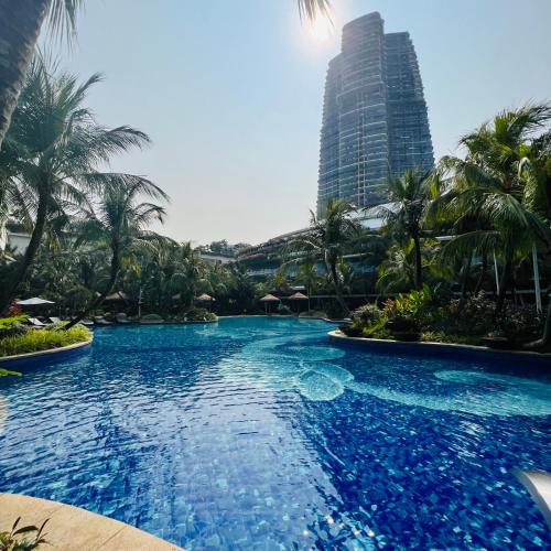 a large pool with palm trees and a tall building at Seaview 2B1R 4 pax Condo Forest City 1G-2908 in Gelang Patah