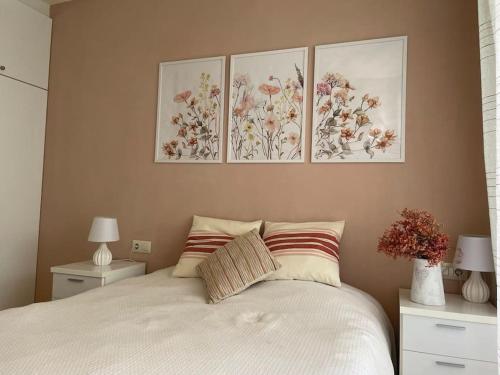 1 dormitorio con 3 cuadros en la pared sobre una cama en Charming Garden Apartment en "Jardins de Sa Boadella" en Lloret de Mar