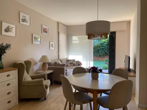 sala de estar con mesa, sillas y sofá en Charming Garden Apartment en "Jardins de Sa Boadella" en Lloret de Mar
