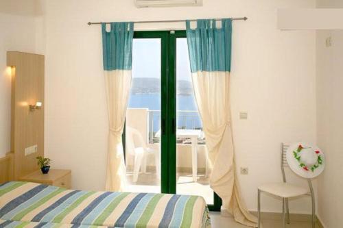 a bedroom with a bed and a sliding glass door at Aptera Paradise With Sea View in Megála Khoráfia