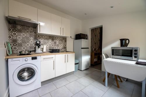 une cuisine avec un lave-linge et un micro-ondes dans l'établissement La Perle de Cognac, à Cognac