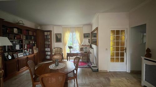 ein Esszimmer mit einem Tisch und Stühlen sowie ein Zimmer in der Unterkunft Belle Maison Individuelle in Rueil-Malmaison