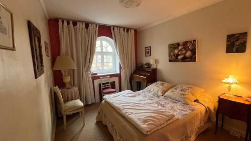 a bedroom with a bed and a chair and a window at Belle Maison Individuelle in Rueil-Malmaison