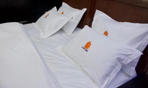 uma cama branca com almofadas brancas em The Hidden Gem Wuye em Abuja