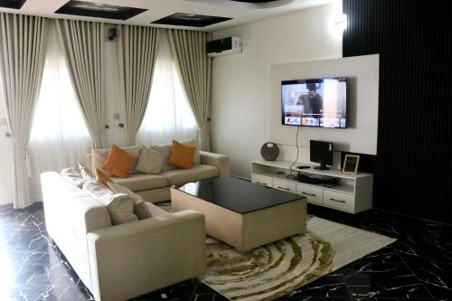 uma sala de estar com um sofá e uma televisão em The Hidden Gem Wuye em Abuja