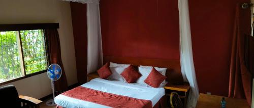 a bedroom with a bed with red and white pillows at Kafka Gardens in Kisumu