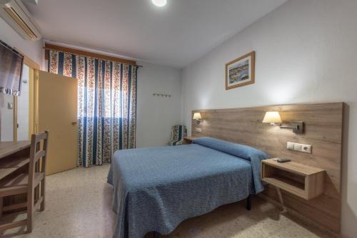 a bedroom with a blue bed and a wooden headboard at Hotel San Andres in Jerez de la Frontera