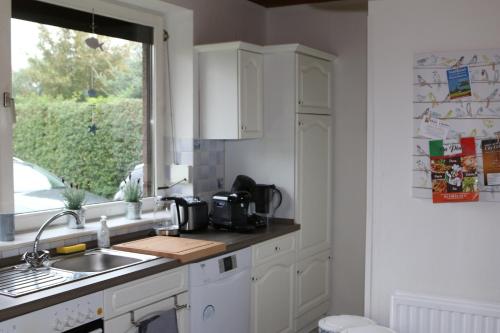 a kitchen with white cabinets and a sink and a window at Haus Seewind in Wesselburen