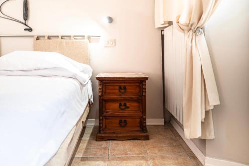 a bedroom with a bed and a wooden dresser next to a night stand at Il risveglio del Poggio in Castiglione dʼOrcia