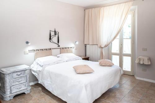 a white bedroom with a bed and a window at Il risveglio del Poggio in Castiglione dʼOrcia