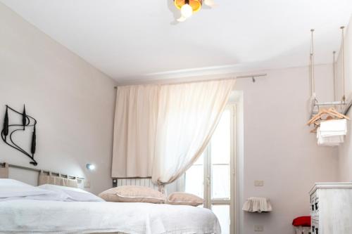 a white bedroom with a bed and a window at Il risveglio del Poggio in Castiglione dʼOrcia