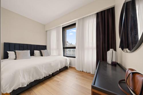 a white bedroom with a large bed and a window at King David Apartment - J&J in Jerusalem