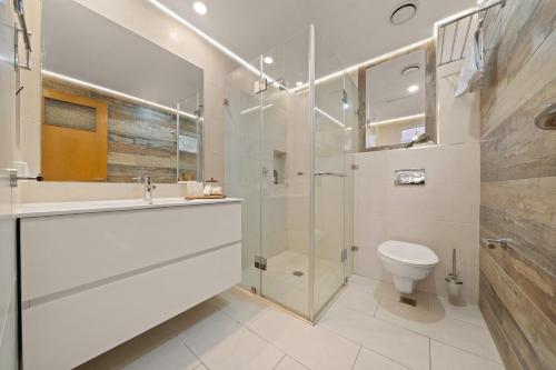 a white bathroom with a shower and a toilet at King David Apartment - J&J in Jerusalem