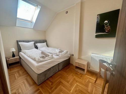 a small bedroom with a bed and a window at Agape Villa Apartments in Novi Sad