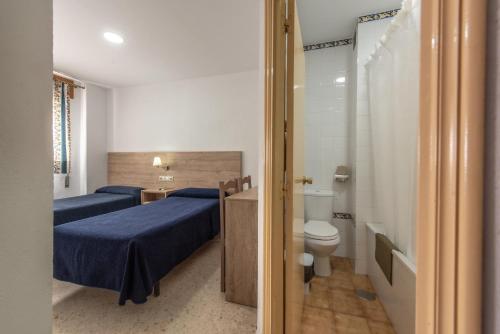 ヘレス・デ・ラ・フロンテーラにあるホテル サン アンドレスのベッド2台、トイレ、バスルームが備わる客室です。