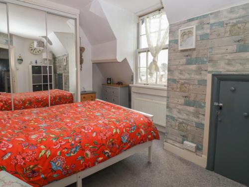 a bedroom with a bed with a red comforter at Stone's Throw in Budleigh Salterton