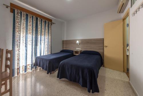 a room with two beds and a window at Hotel San Andres in Jerez de la Frontera