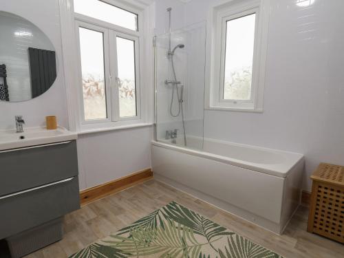 uma casa de banho com uma banheira, um lavatório e janelas em Stone's Throw em Budleigh Salterton