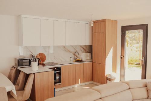 a kitchen with white cabinets and a couch in a room at Bujtina e Gjyshes in Peje