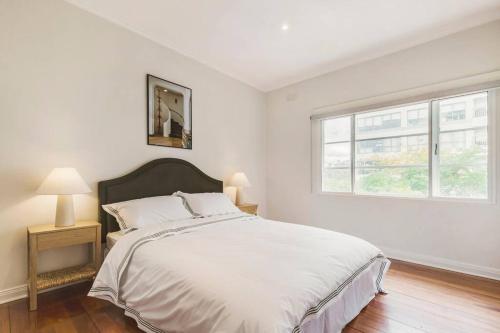 Un dormitorio blanco con una cama grande y una ventana en The Queen's Suite - Boutique Art Deco Charm, en Melbourne