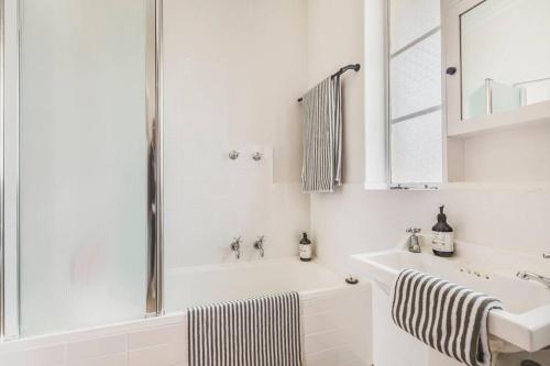 un bagno bianco con vasca e lavandino di The Queen's Suite - Boutique Art Deco Charm a Melbourne