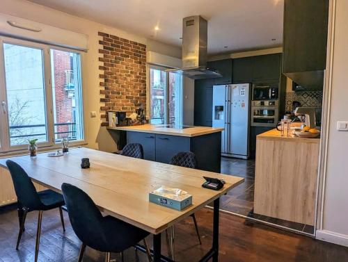 uma grande cozinha com uma mesa de madeira e cadeiras em Appartement proche JO 2024 - RER Drancy em Drancy