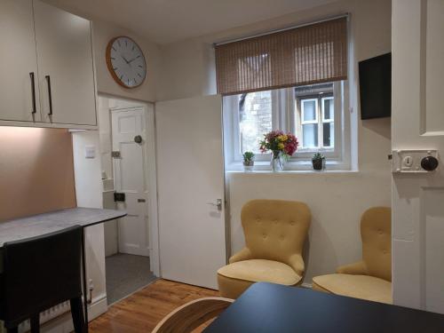 uma cozinha com duas cadeiras e um relógio na parede em Trade Digs - Contractors Accommodation - Stroud 