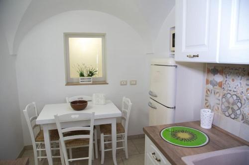 eine Küche mit einem weißen Tisch und einem weißen Kühlschrank in der Unterkunft Cummersa Mazzini casa tipica nel Centro storico DI Locorotondo in Locorotondo