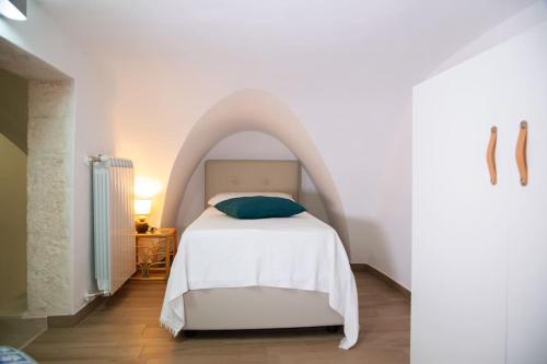 ein Schlafzimmer mit einem weißen Bett mit einem Bogen in der Unterkunft Cummersa Mazzini casa tipica nel Centro storico DI Locorotondo in Locorotondo
