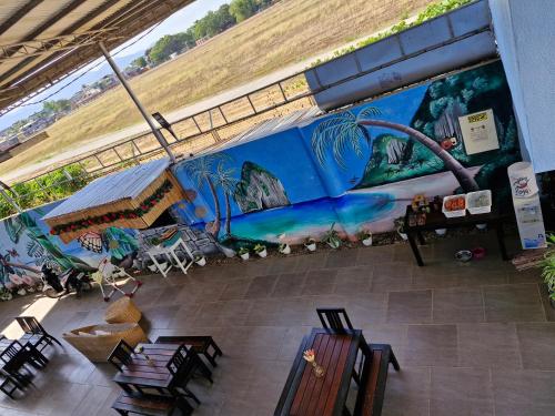 Un mural en el costado de un edificio con mesas y sillas. en Buenas Pension House, en Puerto Princesa City